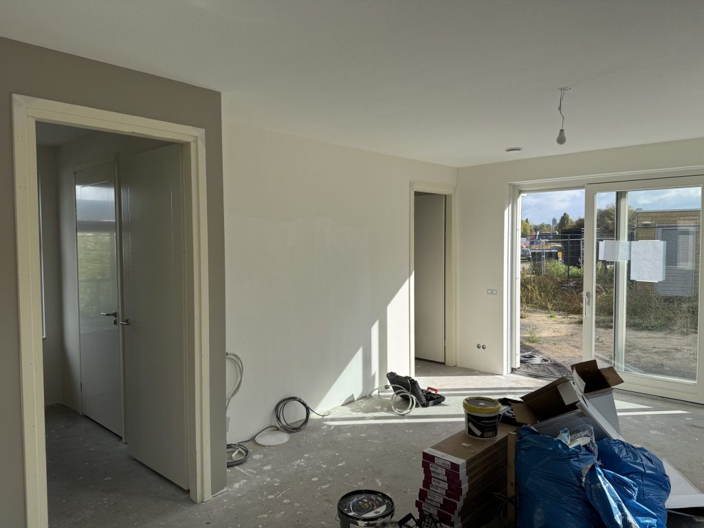 Woonkamer tijdens de klus, met emmers en materiaal klaar voor de behanger