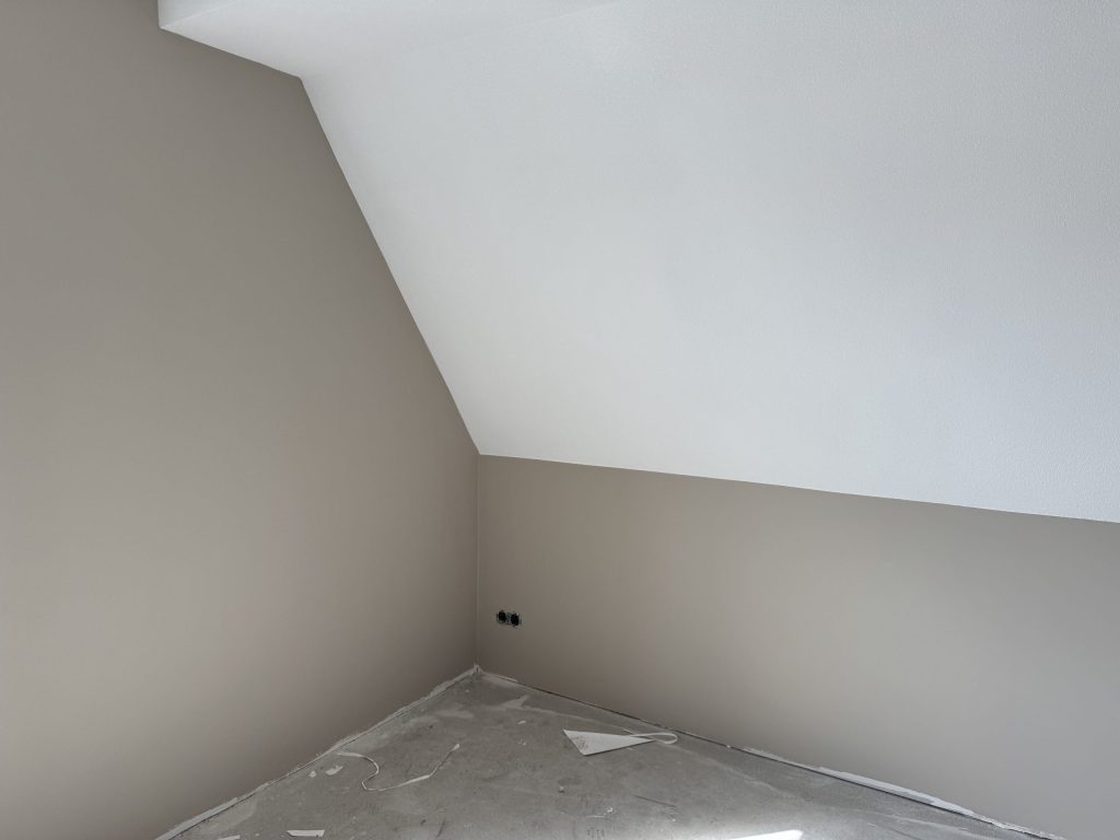 Zolderkamer met schuine wand, afgewerkt in een zachte zandkleur en wit